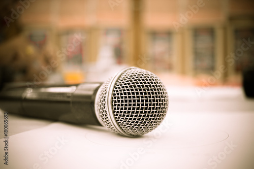 Microphone on abstract blurred of front podium and speech in seminar room or speaking conference hall light, Event meeting bokeh background, black and white tone