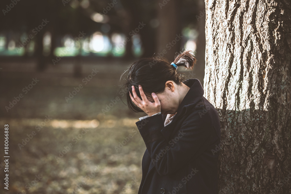 木にもたれて落ち込む女性 Stock Photo Adobe Stock