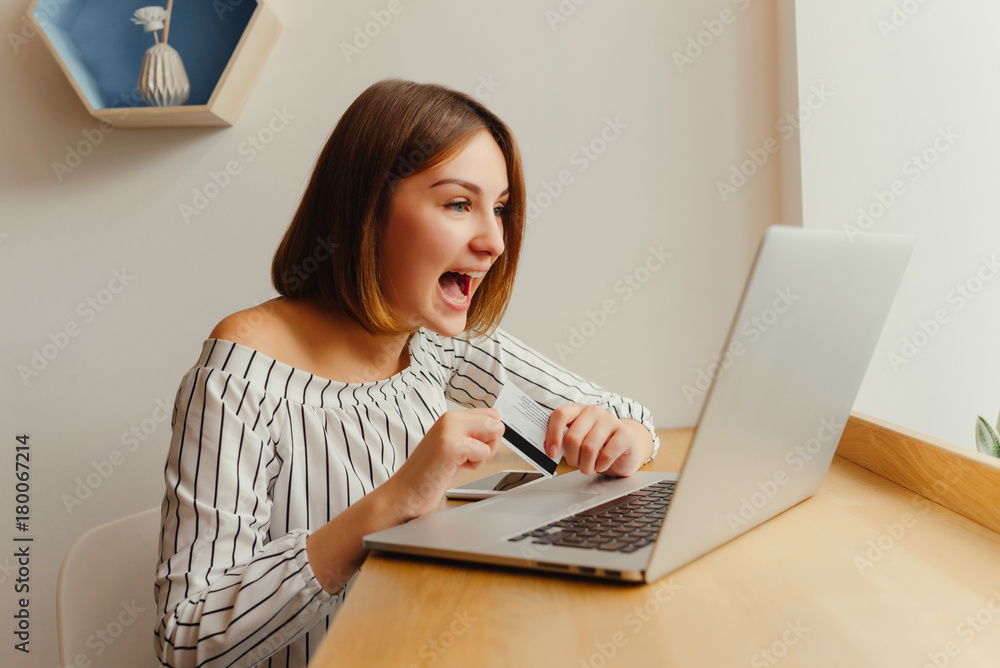 Very joyful woman holding credit card and using laptop computer. Online shopping concept. Payment Transaction at Computer using Credit Card Very joyful woman holding credit card and using laptop computer. Online shopping concept. Payment Transaction at Computer using Credit Card