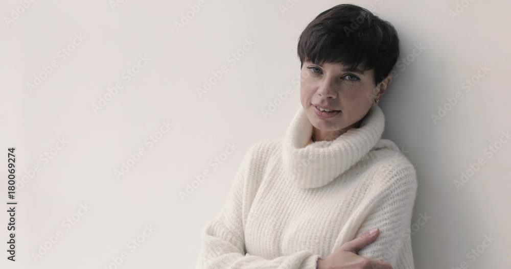 Portrait of young charming woman with short haircut posing in white sweater looking at camera. Portrait of young charming woman with short haircut posing in white sweater looking at camera.