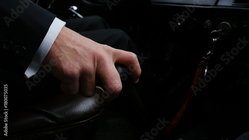 Businessman driving to work, hand shifting the gear stick. Businessman shifts the transmission in the rare machine. Businessman driving car hand shifting the gear stick. Retro style