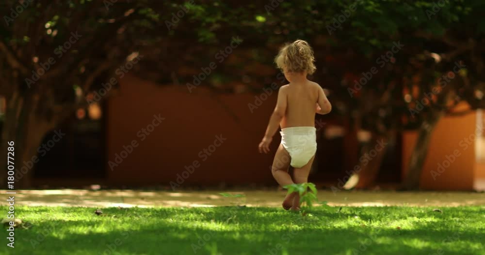 Infant child walking outside in the sunlight wearing diapers in 4k clip
