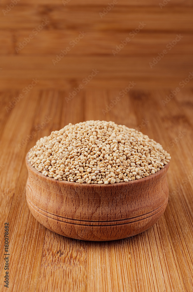 Quinoa in wooden bowl on brown bamboo board, closeup. Quinoa in wooden bowl on brown bamboo board, closeup.