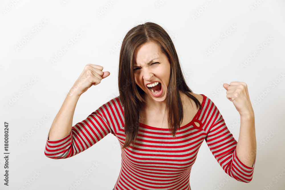 Fototapeta premium Pretty European young angry brown-haired woman with healthy clean skin, dressed in casual red and grey clothes, screaming, swearing and waving her arms, on a white background. Emotions concept.