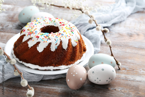 Bundt cake with sprinkles and easter eggs on wooden table photo