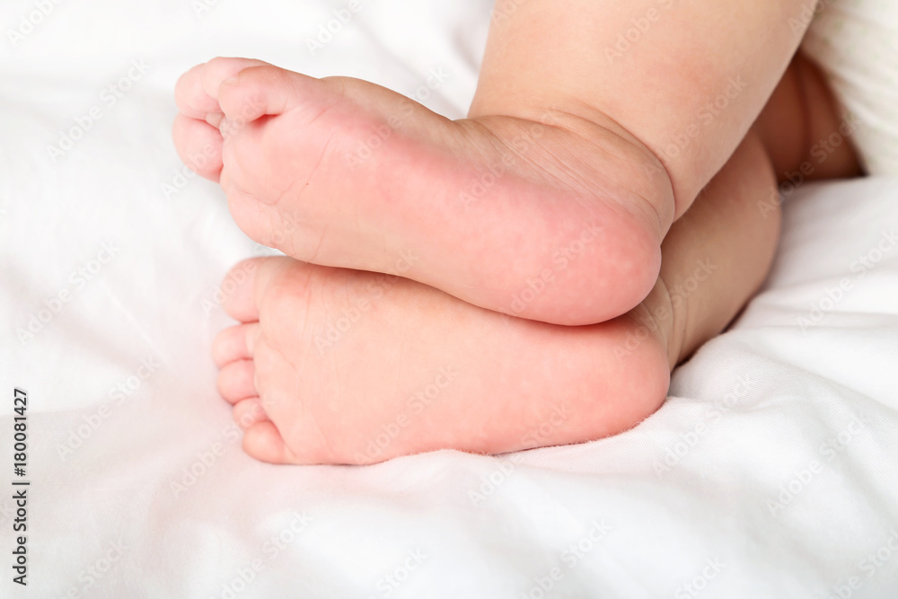 Newborn baby feet on white bed