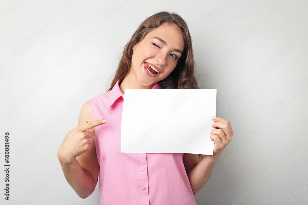 Young woman with blank paper on grey background Young woman with blank paper on grey background