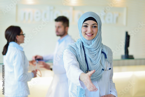 Young happy smiling female muslim doctor giving hand for handshaking