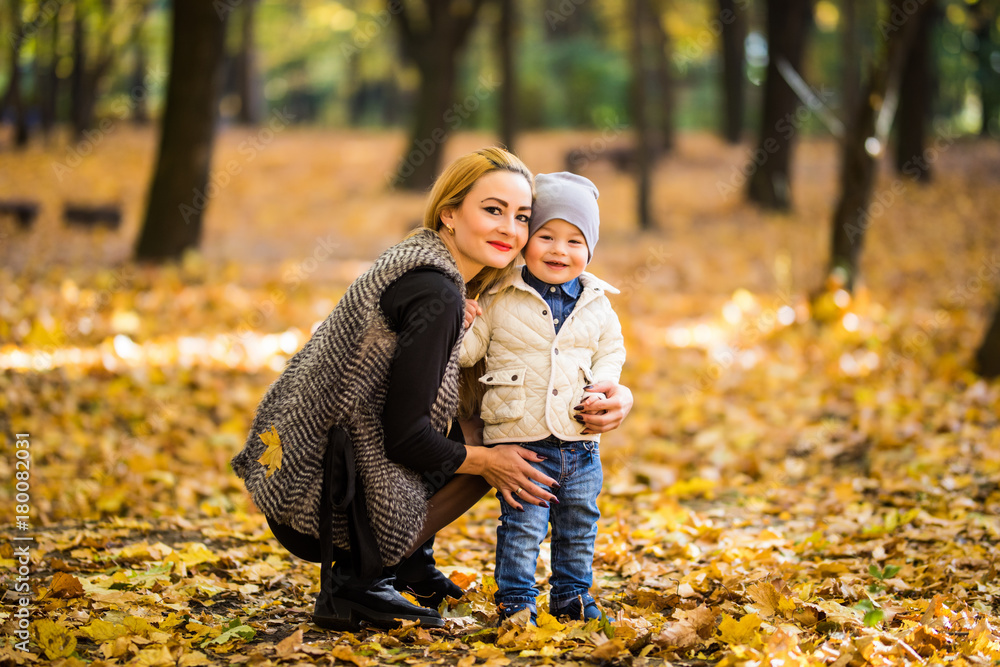 Fototapeta premium Happy mother and son are playing in the autumn park