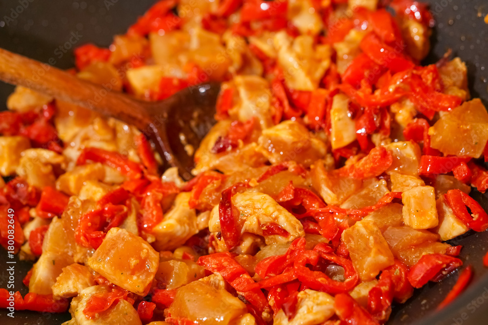 Preparation of cutted paprika with chicken meat in black frying pan Preparation of cutted paprika with chicken meat in black frying pan