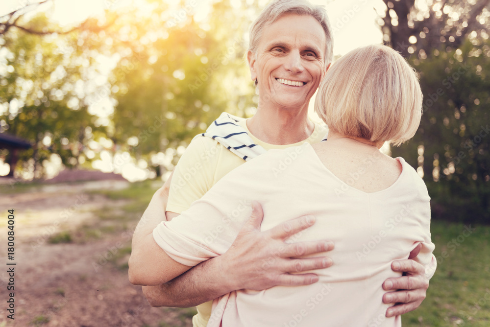 True feelings. Handsome happy elderly man smiling and hugging his wife while expressing his feelings True feelings. Handsome happy elderly man smiling and hugging his wife while expressing his feelings