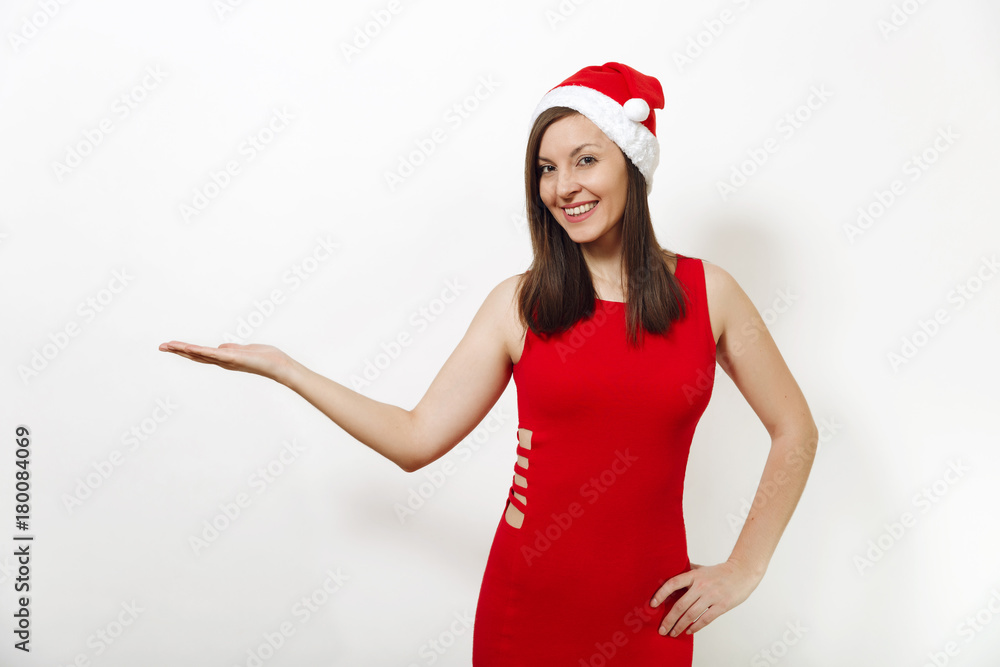 Pretty caucasian happy woman with charming smile wearing red dress and Christmas hat looking camera, holding copy space on palm isolated on white background. Santa girl. New Year holiday 2018 concept Pretty caucasian happy woman with charming smile wearing red dress and Christmas hat looking camera, holding copy space on palm isolated on white background. Santa girl. New Year holiday 2018 concept