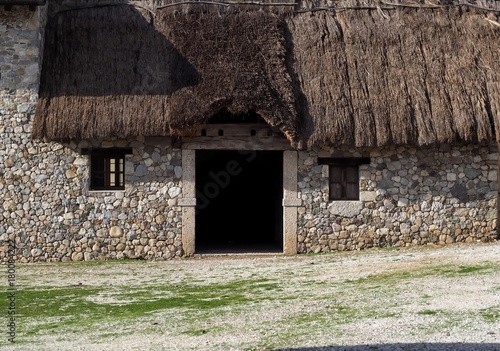 Entrance of an old rural stone building with thatched roof