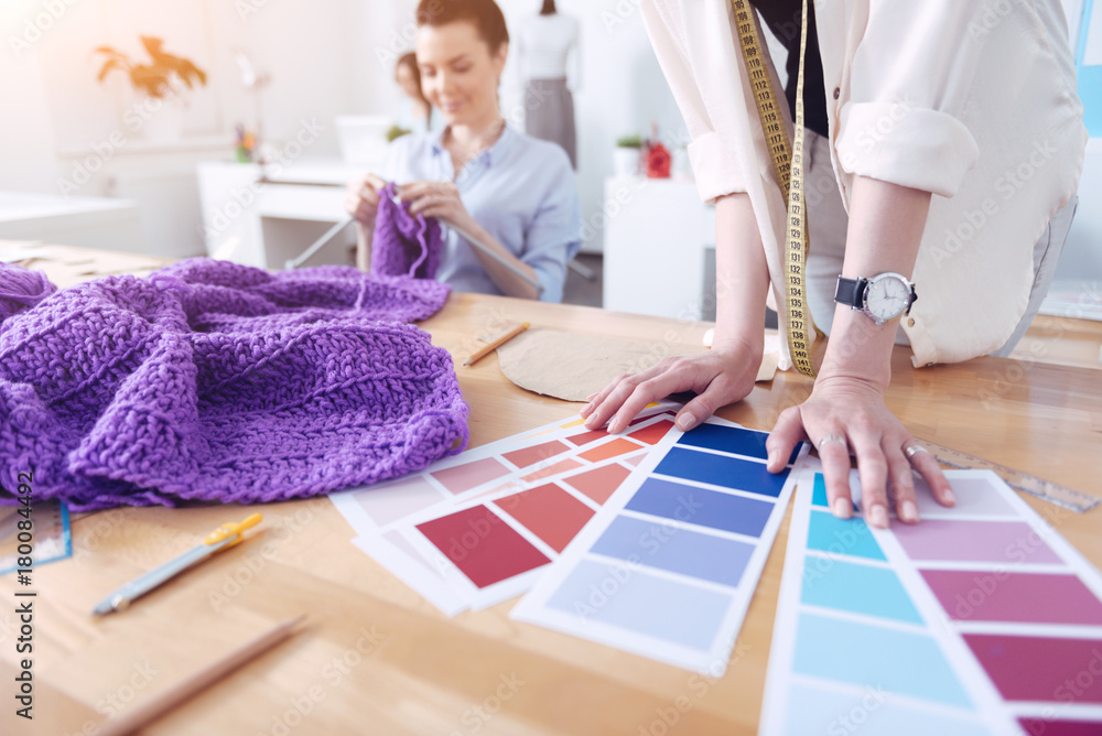 Fototapeta premium Choosing colors. Talented young designer showing bright color palettes to her clients