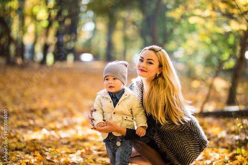 Mother and little son in park or forest  outdoors. Hugging and having fun together in autumn park