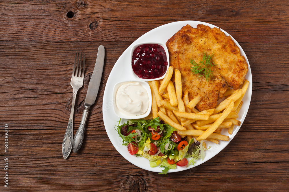 Chicken schnitzel, served with fries and salad. Chicken schnitzel, served with fries and salad.