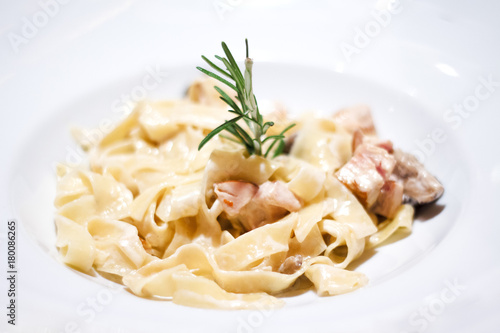 pasta cream sauce with chicken, decorated with thyme on a white plate .