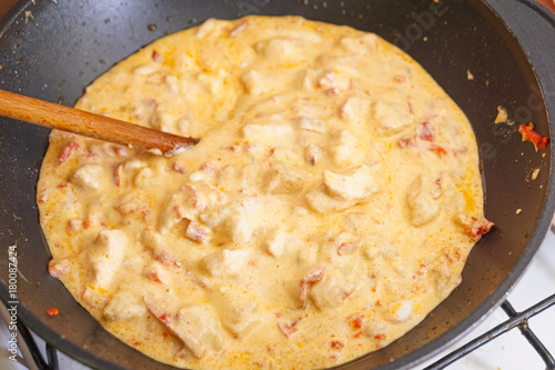 Preparation of cutted paprika with chicken meat and cheese in black frying pan