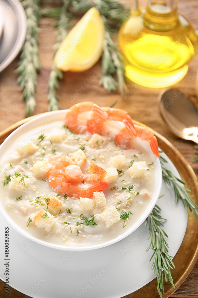 Tasty cream soup with fresh shrimps and croutons in bowl on table Tasty cream soup with fresh shrimps and croutons in bowl on table
