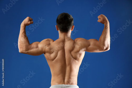 Muscular young man on color background