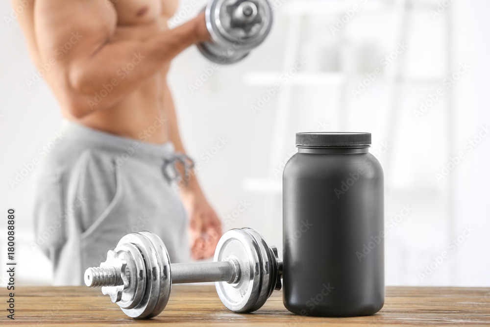 Dumbbell and jar with protein powder on table Dumbbell and jar with protein powder on table