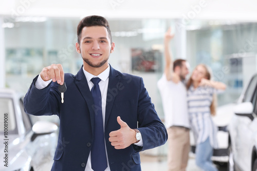 Car salesman holding key in...