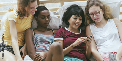 A group of diverse women lying on bed and using mobile phones