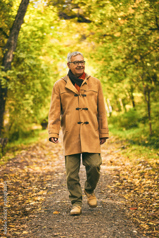 Happy senior man walking in park in autumn. 