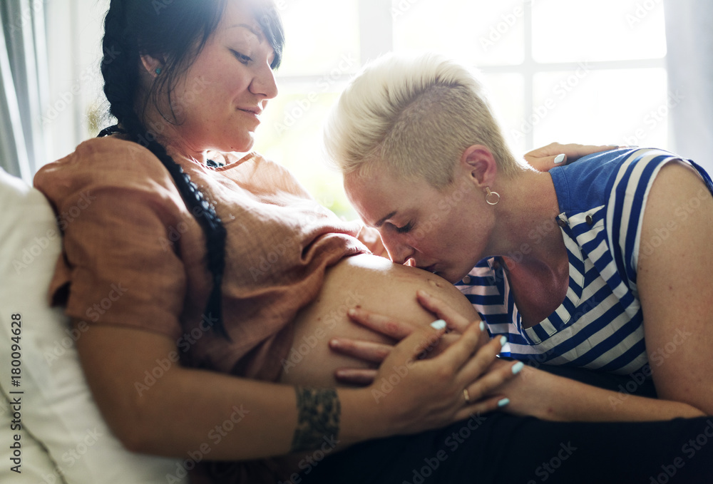 Woman kisses her partner's pregnant belly Woman kisses her partner's pregnant belly