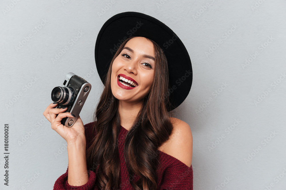 Pretty cheerful woman in black hat holding retro photo camera Pretty cheerful woman in black hat holding retro photo camera