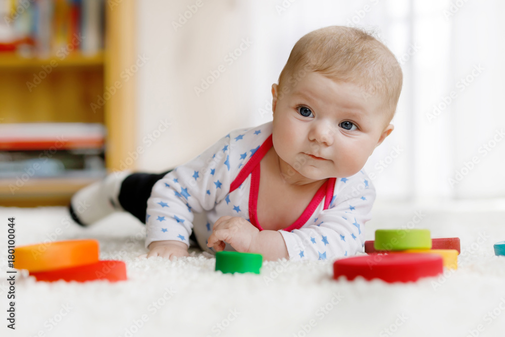 Cute baby girl playing with colorful wooden rattle toy Cute baby girl playing with colorful wooden rattle toy