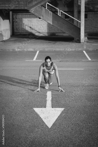 Female athlete ready for running and training on urban asphalt. Sporty woman working out outdoor.