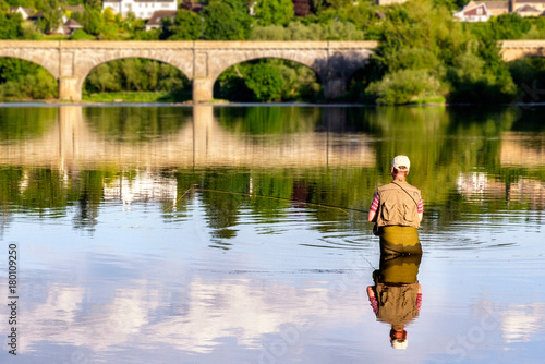 Man fly-fishing on the River Tweed with the iconic Kelso Bridge at the background. Kelso, Scottish Borders, Scotland, UK