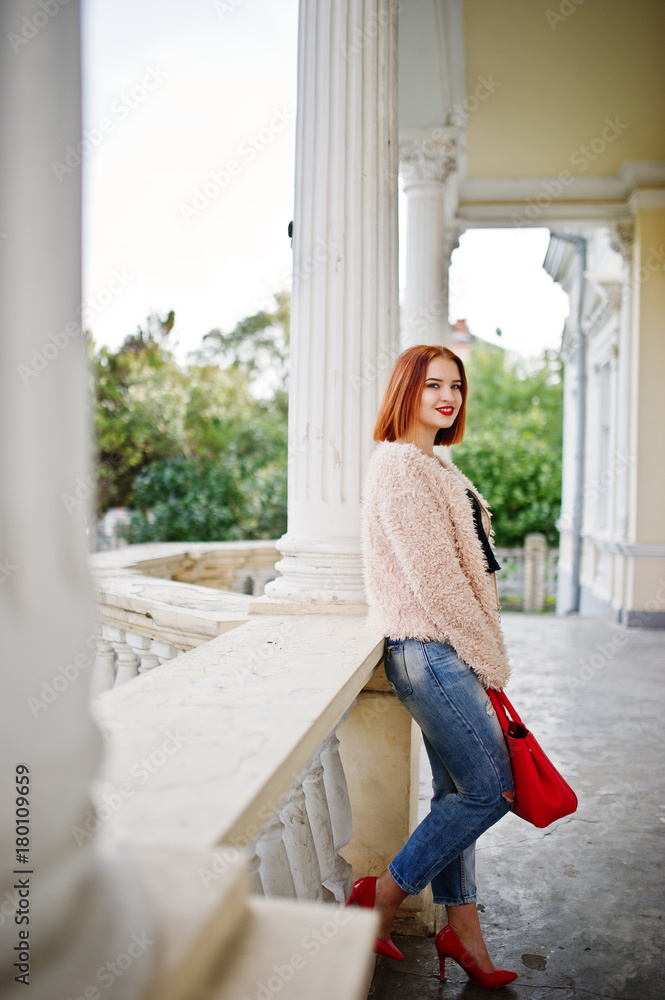 Red haired girl with red handbag posed near vintage house. Red haired girl with red handbag posed near vintage house.