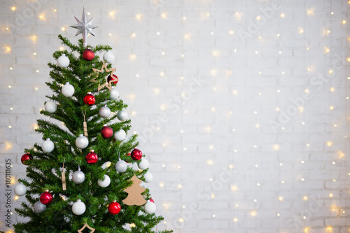 decorated christmas tree over white brick wall with lights