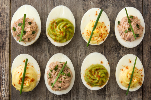 Variety of stuffed eggs with avocado and tuna on wooden table.Top view