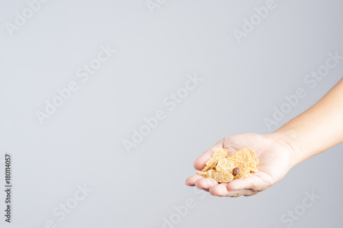 Hand with crispy whole wheat grain cereal, with mixing dry fruits from pineapple, papaya and raisin