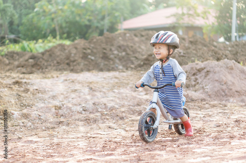 Asian boy about 1 year and 9 months is riding baby balance bike on muddy construction road