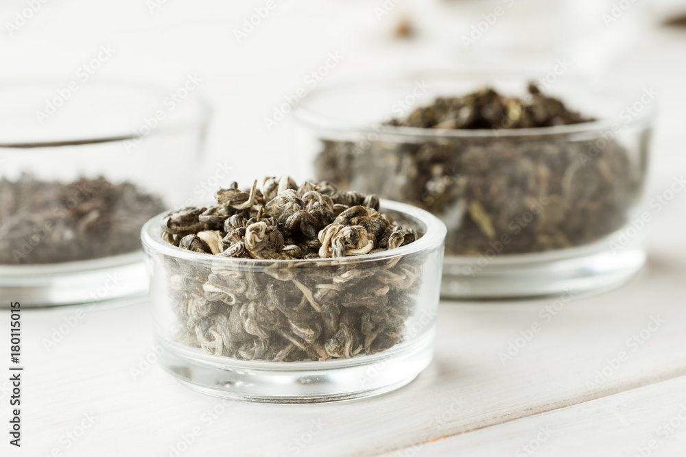 Different dry tea in a small glass dishes on a white wooden table Different dry tea in a small glass dishes on a white wooden table