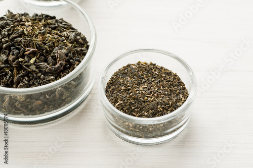 Different dry tea in a small glass dishes on a white wooden table