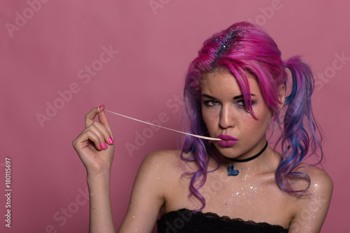 Portrait of attractive heavily made up girl in black top and heart-shaped choker. Stretching her gum