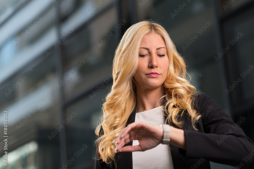 Young businesswoman checking the time on her wristwatch Young businesswoman checking the time on her wristwatch