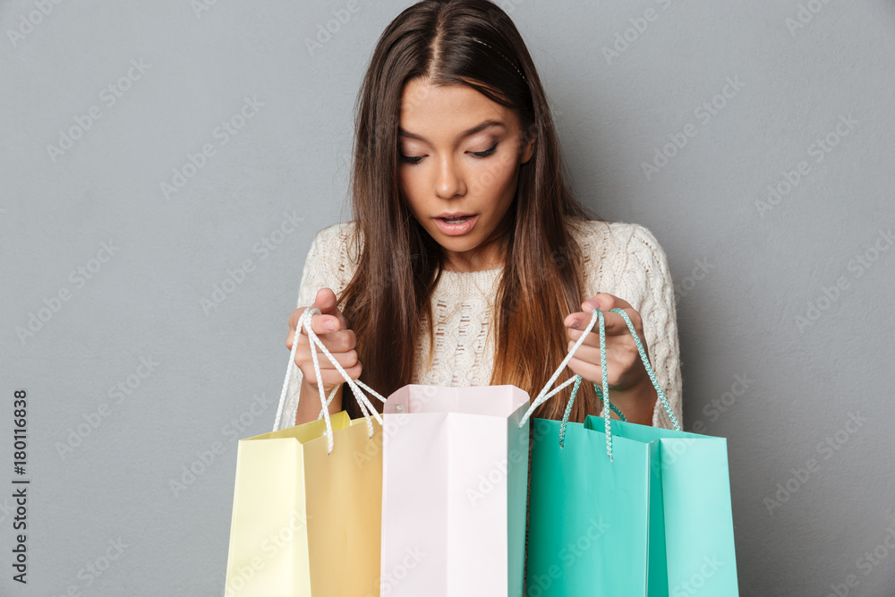 Surprised brunette woman in sweater looks at packages