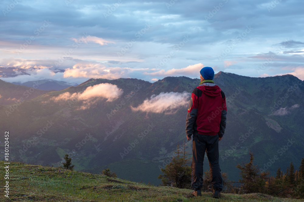 Fototapeta premium Traveler in the mountains admires sunset after storm