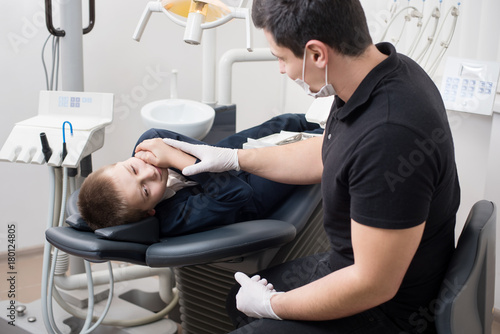 Boy patient with toothache complaining to pediatric dentist at dental clinic office. Medicine  dentistry and health care concept. Dental equipment