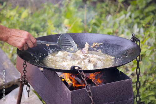 Fresh fish fried in large restaurant frying pan.