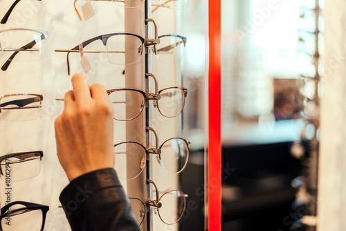 Close up of woman taking glasses from shelf.
