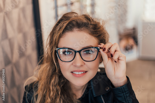 Portrait of smiling female customer wearing spectacles in optical store.