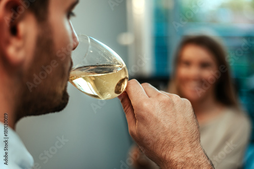 Close up of man drinking wine, woman in background.