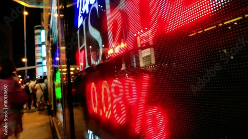 Pedestrians walk past a financial display board in Hong Kong